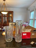 Two clear crystal vases and a tall crystal wine cooler on a countertop, with boxes and packaging visible in background.