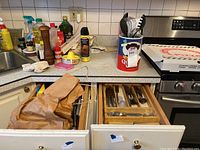 Drawer with wooden organizer containing mixed flatware: knives, forks, spoons.