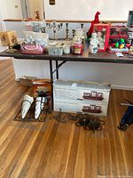 Wide view of table showing candles, figurines, boxed ledge and frame sets, sconce planters on floor, and other decorative items.
