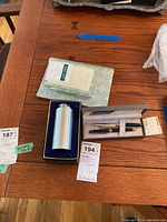 Colibri pen and letter opener in their gift box alongside a silver table lighter in another box and a small calendar booklet on the table