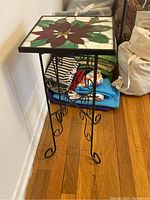 Wrought iron plant stand with square stained glass top showing floral design from an angle