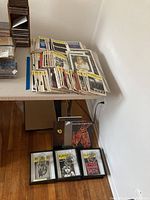 Full assortment of original vintage playbills stacked on table, with several framed playbills and three glasses on floor underneath.