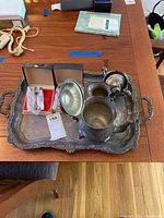Photo of silverplate tray holding tea set items and demitasse spoons in box on wood table