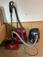 Front view showing both vacuums, hoses, floor heads, and handles.