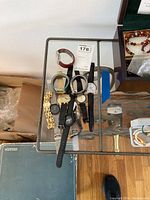 11 watches laid out on a glass table with various metal, leather, and rubber straps visible.