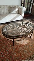 Front view of oval glass top coffee table on patterned rug
