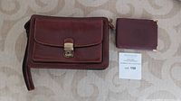 Brown Giudi leather purse with strap and matching wallet displayed on fabric background