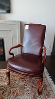 Full view of burgundy leather and wood framed chair with nailhead detail, showing overall condition.