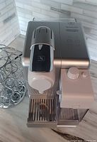 Front view of Nespresso Lattissima Touch coffee machine showing milk frother and pod carousel beside it on marble countertop