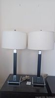 Front view of both lamps on a dark table against a white wall