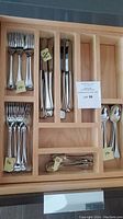 Wooden drawer organizer holding forks, knives and spoons with quantity labels