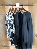 Overview of five garments hung on metal rack, showing style variety and colors