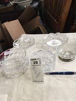 Five cut glass bowls displayed on table, showing a variety of cuts and styles including Waterford bowl with silver rim