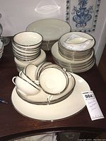 Stack of Franciscan Masterpiece china showing cups, bowls, plates and an oval platter with beige and brown trim.