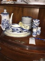 Various pieces of the Hara dish set displayed on a wooden surface including teapot, cups, saucers, and small condiment jars.