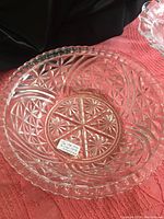 Close-up of first large clear glass bowl showing starburst and geometric patterns with scalloped edge
