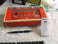 Orange Lionel horse car in original box with clear plastic window, labeled 'Stable of Champions'. Pen shown for scale and lot tag.