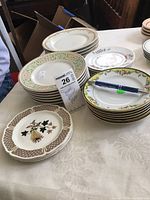 Collection of small floral plates stacked in groups showing various floral borders and designs, close up of general lot