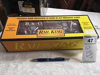 Closed box showing the Rail King B&O round roof freight box car visible through the packaging window with a pen for size reference.