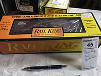 Photo of Rail King branded yellow and black box featuring a B&O stock car in O and O-27 scale with a pen for size reference.