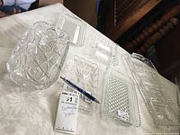 Six rectangular pressed glass dishes laid out on a white tablecloth, showing a variety of patterns including starburst, diamond, hobnail, and floral designs.