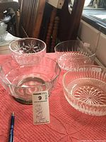 Four deep crystal bowls on table with a price tag, showcasing different cut patterns and the Tiffany stamp on one bowl.