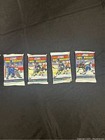 Front view of 4 sealed 1990 Score NHL Hockey Premier Edition card packs laid flat on black background, showing colorful 1990 logo and hockey player artwork.