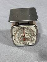 Front view of the vintage Pelouze Model LC-2 postal scale showing the dial with postal rate charts and metal weighing platform.