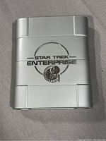 Front of silver collector's case with embossed Star Trek Enterprise logo and emblem.