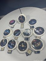 Eleven octagonal plates with Star Trek The Next Generation scenes and starships, displayed with stands and descriptive tags, measuring about 8 inches each.