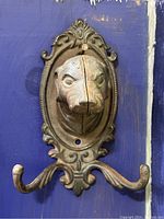 Front view of the vintage dog head wall hook with two hooks mounted on a blue background.