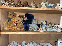 Shelf with assorted plush bears and bear figurines grouped together, showing size and variety.