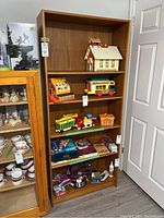 Front angled view of the wood veneer bookcase filled with various items showing condition and shelving.