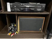 Front view of RCA RP-8065 CD changer, remote on top, beside Epicure speaker and bundled cables