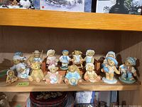 Shelf display of approximately 15 Cherished Teddies bear figurines in various outfits and poses, sized about 1.5 to 4 inches tall.