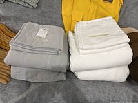 Two folded sets of king-sized flannel sheets in white and light gray colors showing brand tags.
