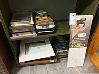 Shelf and multiple stacks of picture frames and mats on a basement shelf