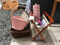 Two wicker baskets and a floral fabric-covered wooden knitting basket with knitting supplies on a light wooden floor.