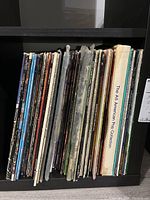 Photo showing approximately 54 LP vinyl records on a shelf, titles vary including children's and pop music.