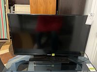 Front view of the Samsung 32-inch TV on glass table with visible screen and bezel.