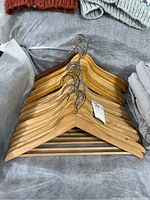 Stack of wooden hangers lying on a gray surface, showing natural wood finish and metal hooks.