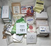 Photo of the full assortment of unopened body, facial, and specialty soaps in their packaging laid out around auction number card.