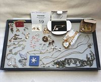Full tray view showing assorted Avon jewelry pieces including earrings, pins, bracelets, necklaces, and a watch along with a miniature sewing box.