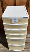 Front view of the top half of a white plastic storage tower with multiple drawers and a flat top surface.