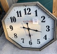 Front view of large Watson octagonal wall clock showing dial with black numerals and hands, brand and design details.