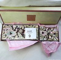 Two trapezoidal Asian lacquer boxes with mother of pearl mosaic designs in original box with pink tissue paper.