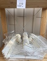 Plastic hangers bundled inside clear plastic bags on a wooden shelving unit, showing quantity and condition.