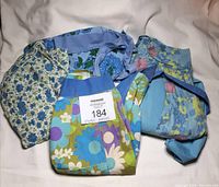 Four handmade vintage cotton aprons folded and laid out together showing variety of floral designs and colors.