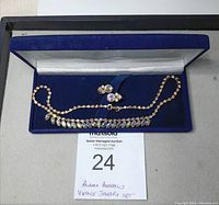 Full view of necklace and earrings set in blue presentation box with auction lot card visible.