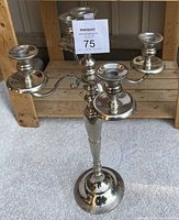 Front view of a large 5-arm silver-tone metal candelabra standing on carpet, showing its height and design.